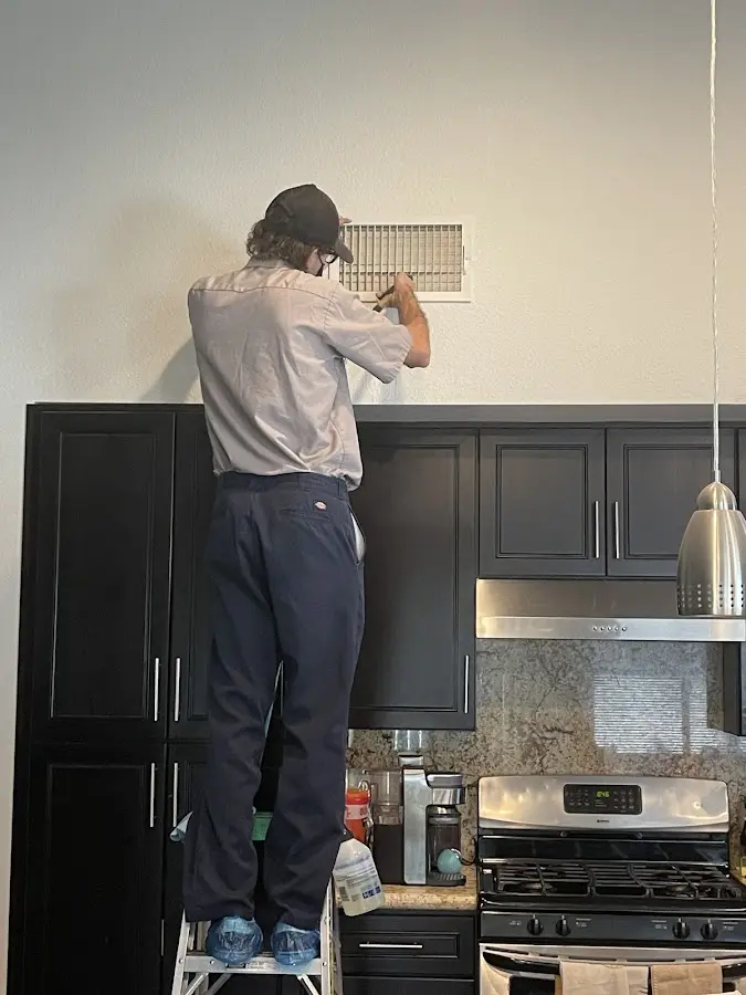 Technician inspecting an air vent during HVAC service in East End